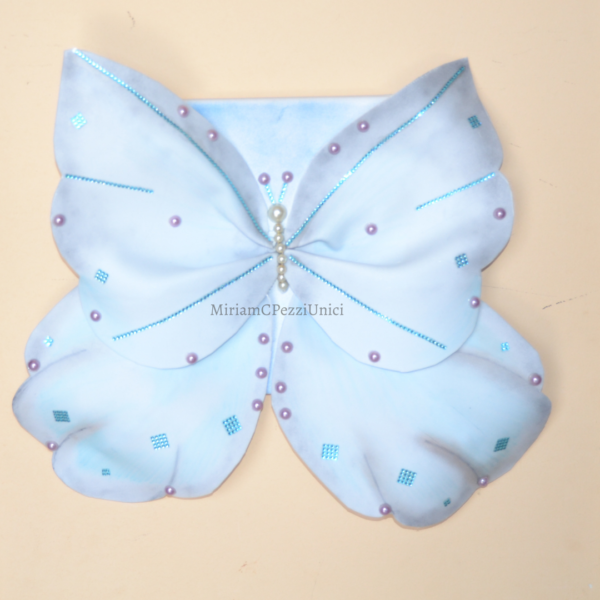 Tela con farfalla in ad ali aperte, decorata con punti luce e perle.